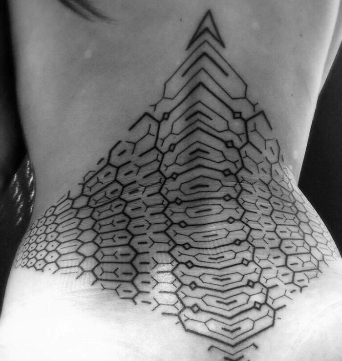 Geometric spine tattoo with intricate patterns, covering the lower back, showcasing artistic precision in black ink.