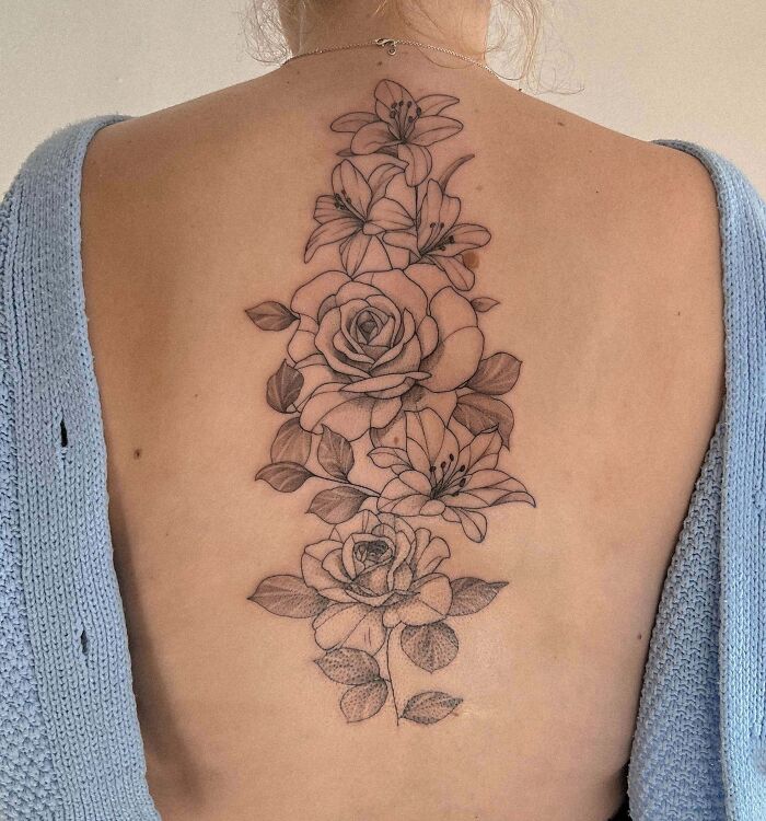 Floral spine tattoo featuring roses and lilies, showcasing intricate details and style.
