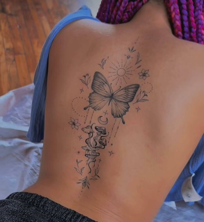 Butterfly and floral spine tattoo design on a person's back.