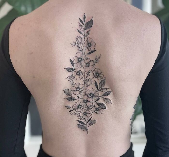 Floral spine tattoo with intricate detailing on a person's back, showcasing elegant tattoo artistry.