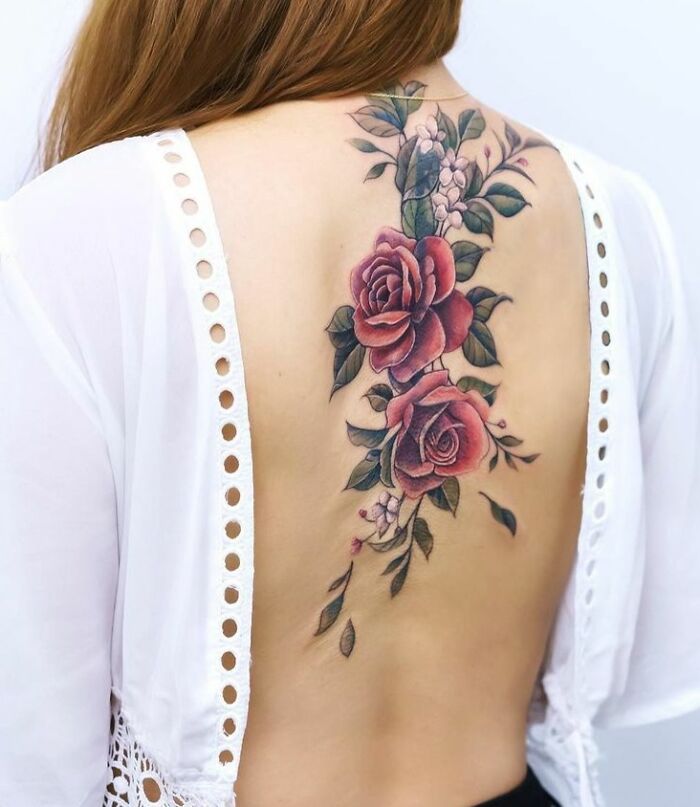 Rose spine tattoo on woman's back, showcasing intricate floral design.