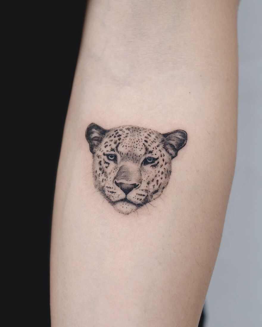 Tattoo of a leopard head with painting-like detail on skin, by Korean ink artist, blending nature and animal elements.