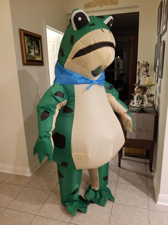 Person wearing a funny inflatable frog costume indoors.