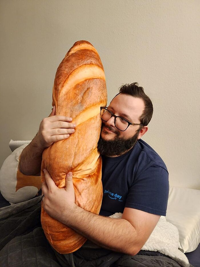Man hugging giant bread-shaped pillow, adding humor to 2024 products.