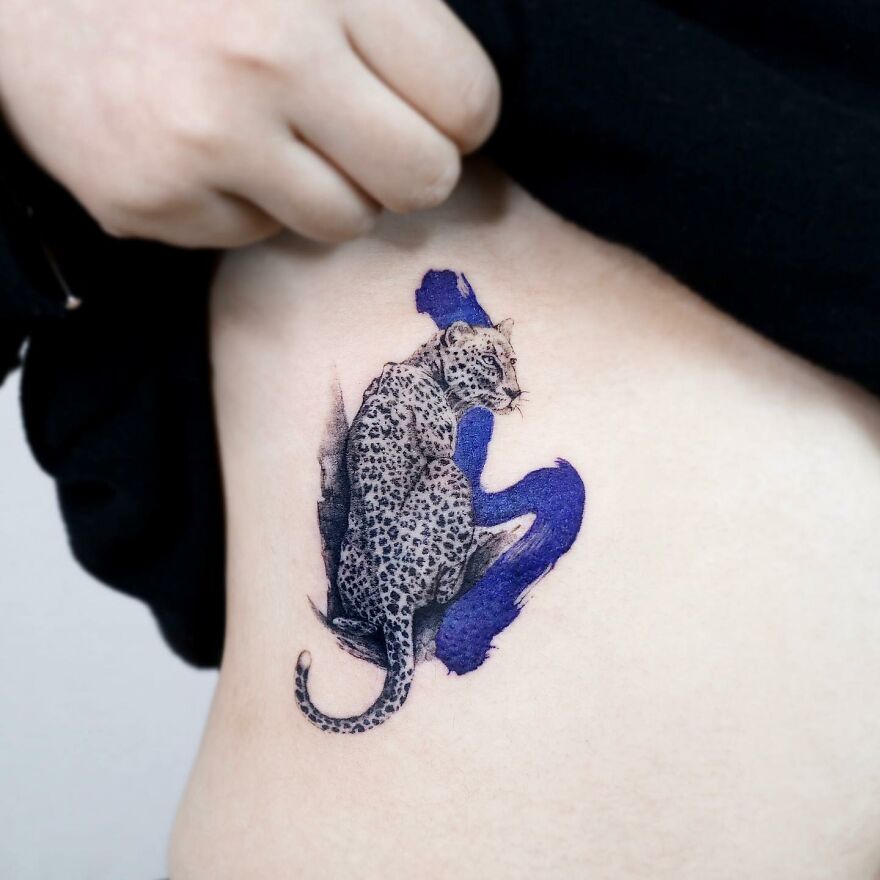 Tattoo of a leopard with painting-like elements on skin, created by Korean ink artist, featuring nature and animal motifs.