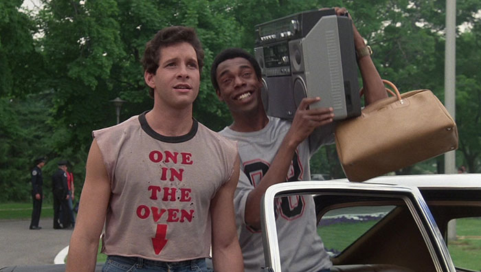 Two people standing one of the is holding a speaker 