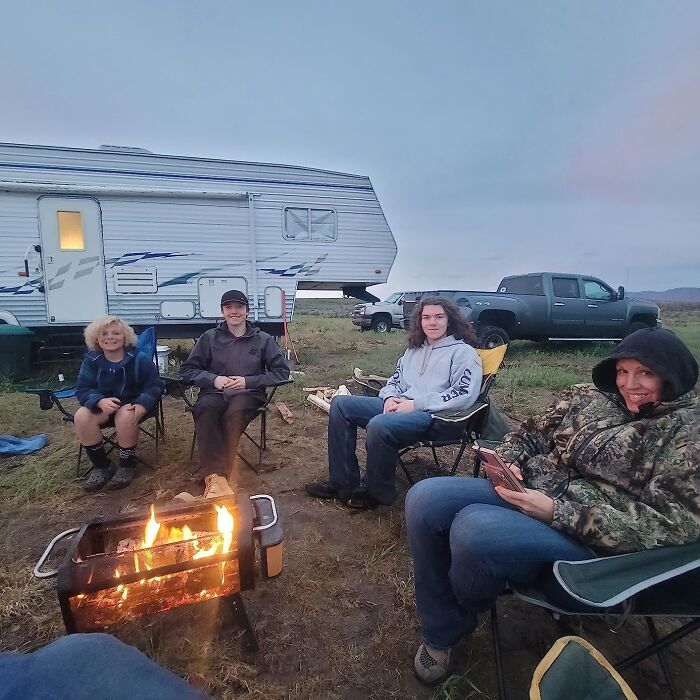 Family enjoying a campfire near camper and truck, perfect for Father's Day finds to spoil your old man outdoors.