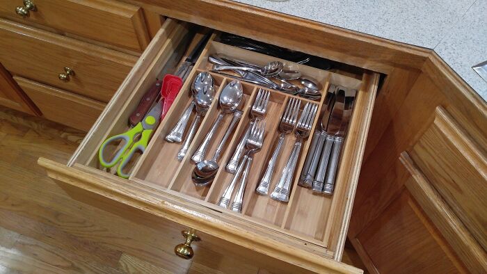 Organised cutlery drawer with utensils and scissors, showcasing a decluttering product for home organisation.