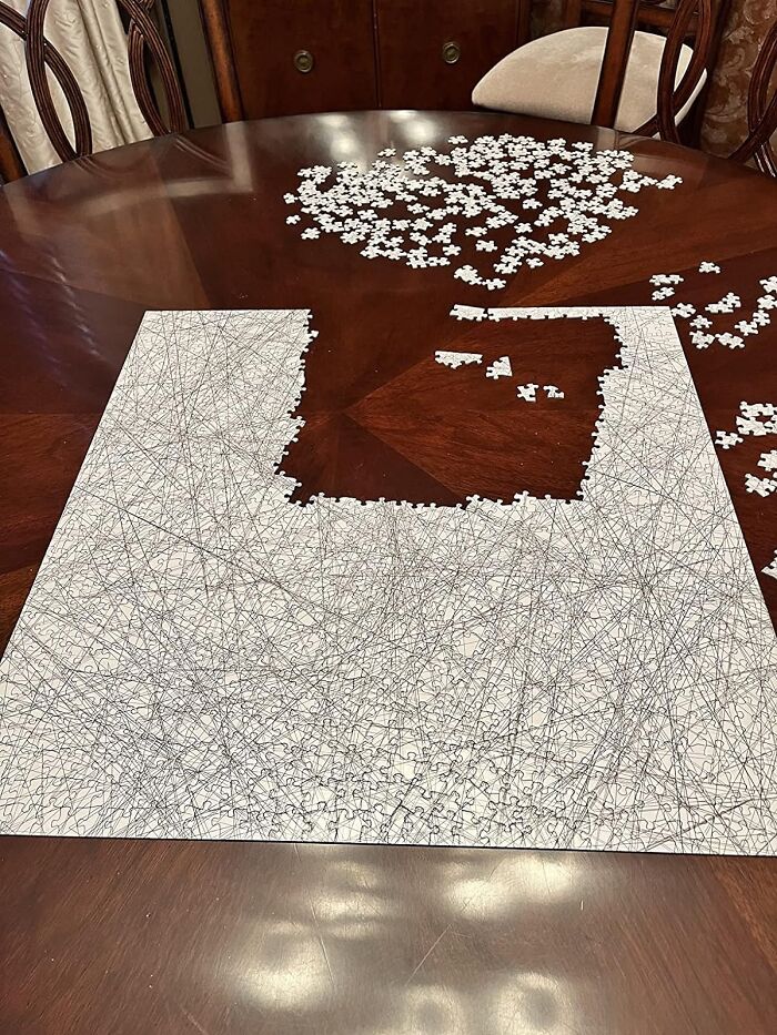 Partially completed humorous puzzle with random lines on a wooden table.