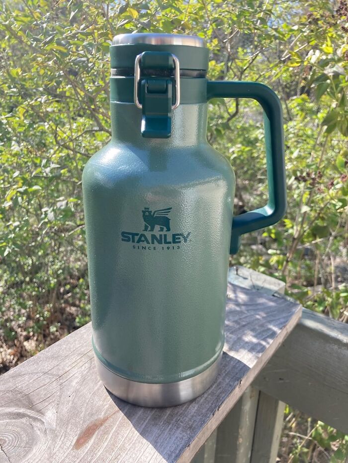 Green Stanley insulated growler with handle on wooden railing outdoors, a top Father's Day finds gift idea.