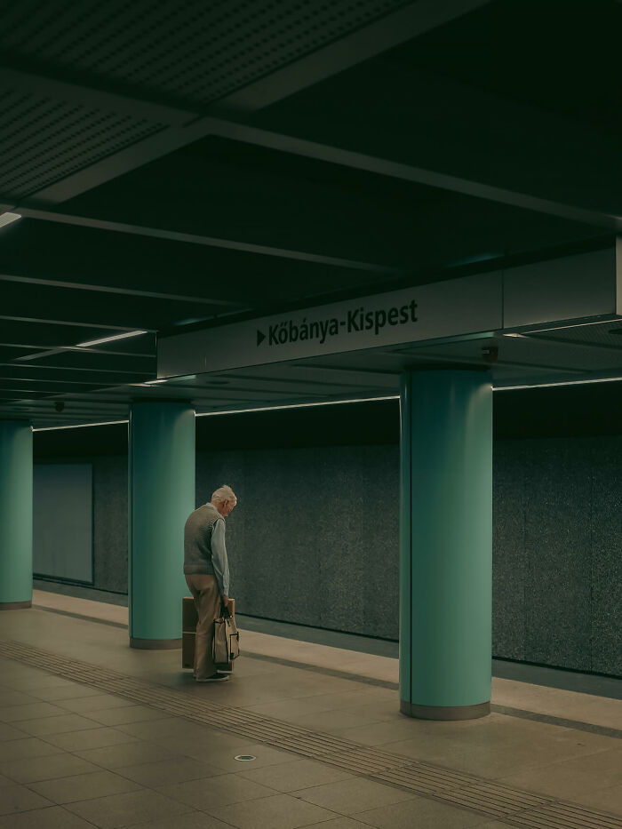 Elderly man waits alone in an urban subway station capturing urban magic with moody lighting and calm atmosphere.
