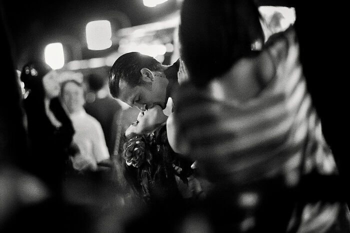 Black and white photo capturing urban magic with a couple sharing an intimate moment amidst a blurred city crowd.