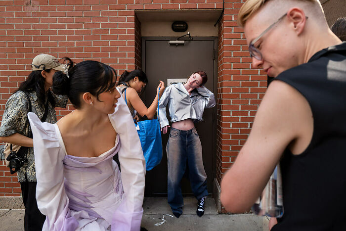Group of people preparing for a photoshoot with urban brick background, capturing urban magic in a candid moment.