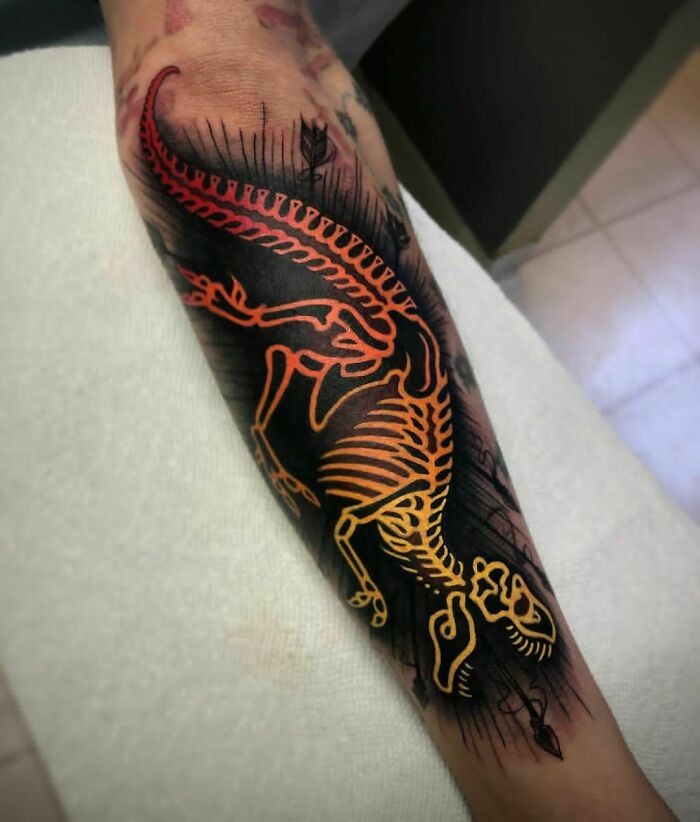 Colorful dinosaur tattoo showcasing a skeleton design on a forearm.