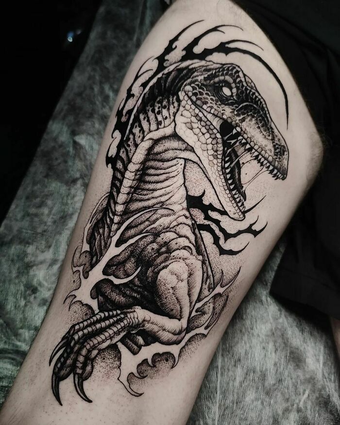 Detailed dinosaur tattoo on a leg, showcasing excellent artistic e*******n and design.