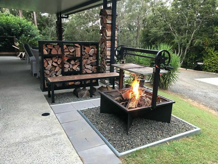 Modern BBQ grill with fire pit and wood storage in a clean backyard, showcasing chic outdoors backyard ideas.