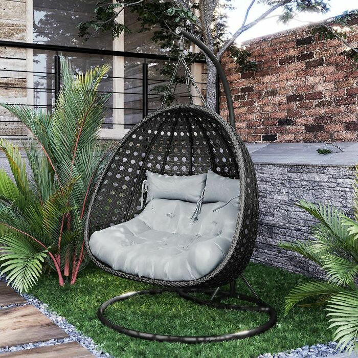 Outdoor swing chair with cushions in a stylish backyard setting, showcasing budget-friendly backyard ideas for chic outdoors.