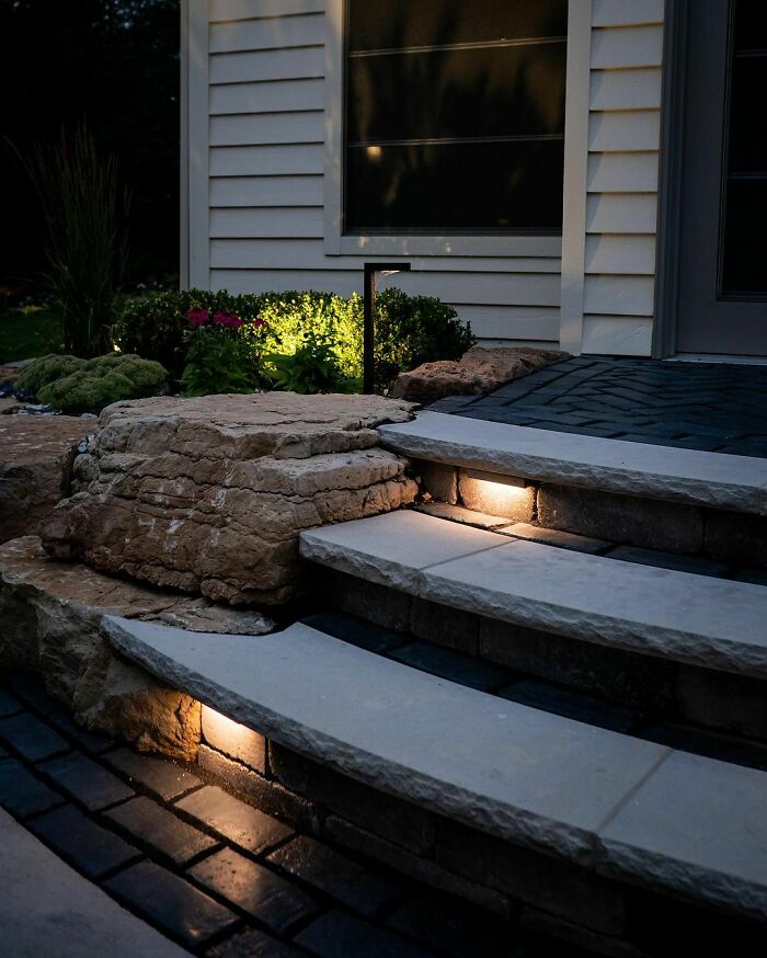 Outdoor lights framing backyard stone steps, creating a chic and budget-friendly backyard ambiance at night.