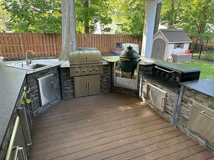 Modern outdoor kitchen in a backyard with stainless steel grills, stone countertops, and wood decking for chic outdoors.