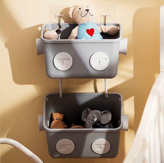 Two gray wall-mounted hanging baskets with toys in it