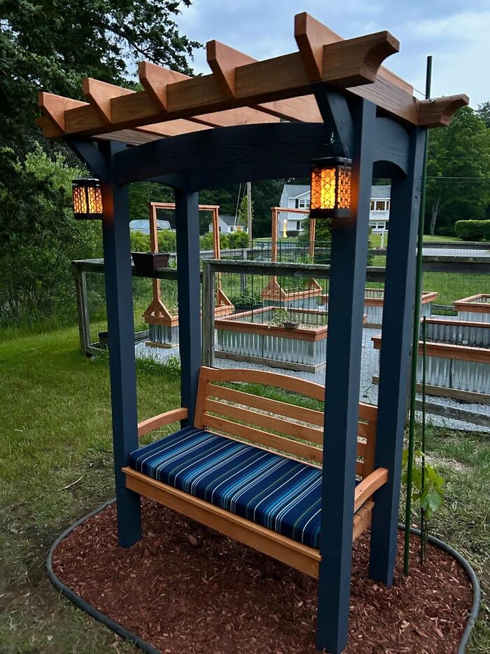 Colorful backyard arbor with wooden bench and lanterns, offering a stylish and budget-friendly outdoor seating idea.