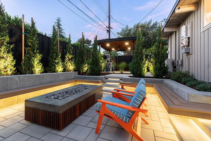 Cozy modern backyard with a fire pit surrounded by stylish seating and lush greenery in chic outdoors design.