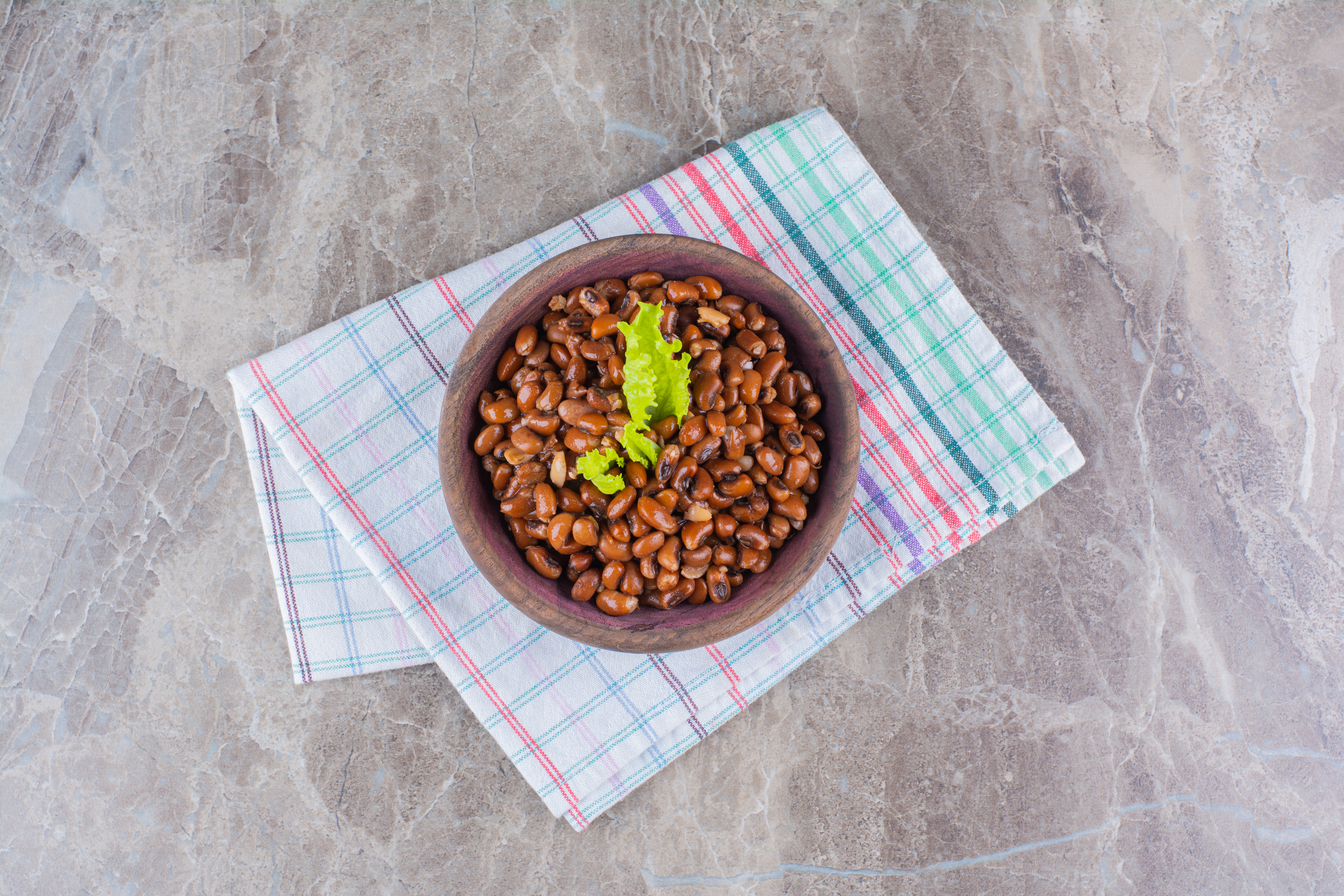Bowl of cooked beans on a checkered cloth, showcasing dog-safe legumes.