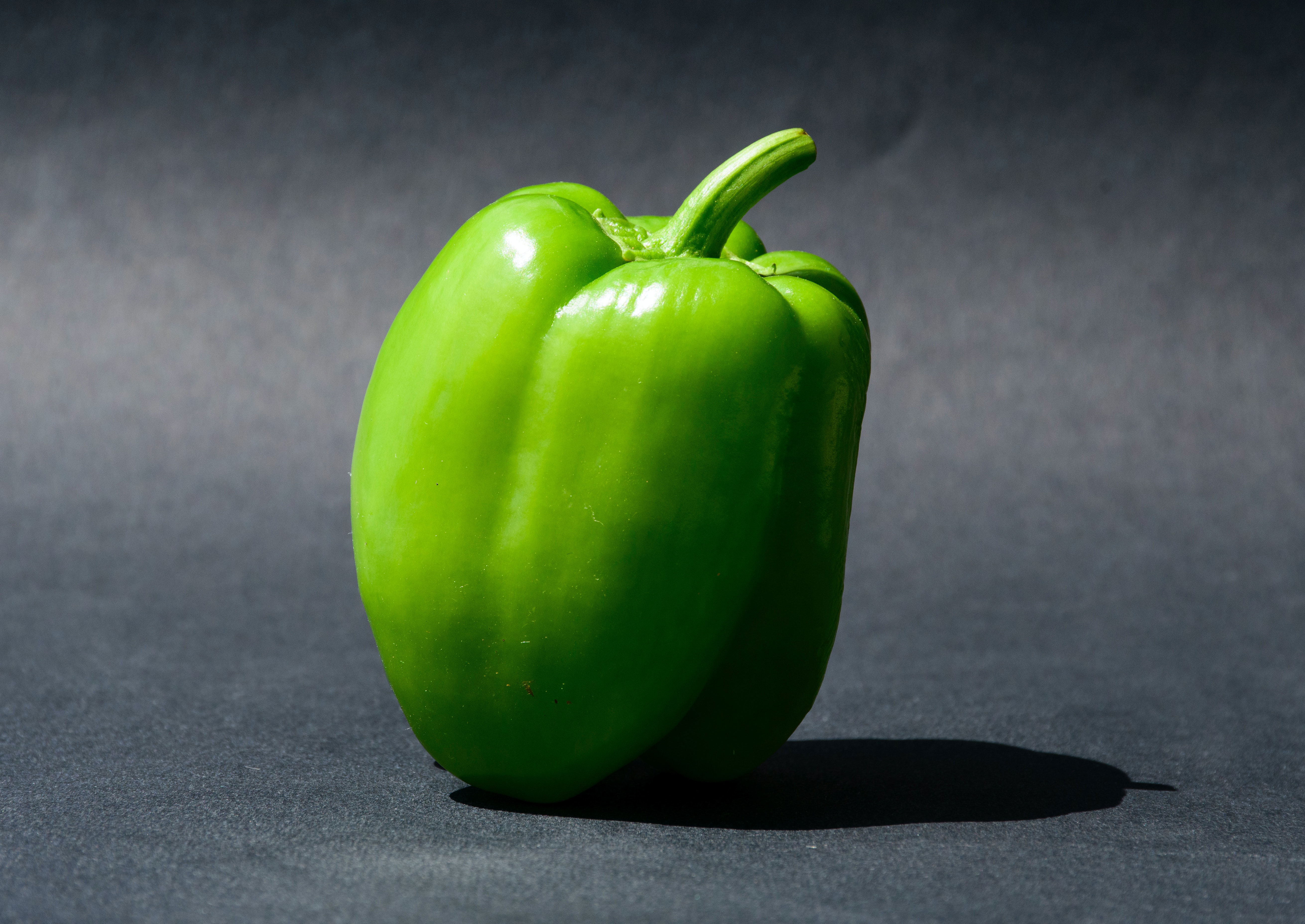 Green bell pepper on a dark background, showcasing benefits for dogs.