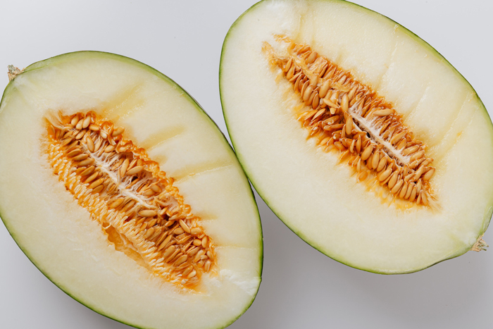 Sliced cantaloupe halves, showcasing seeds and juicy interior, exploring if dogs can eat this fruit.