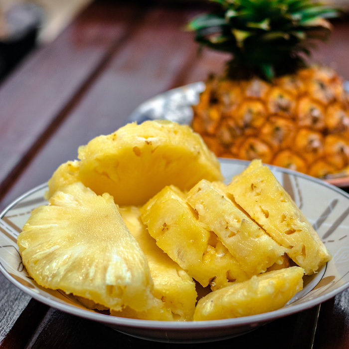 Sliced pineapple on a plate with a whole pineapple in the background. Sliced pineapple on a plate with a whole pineapple in the background.
