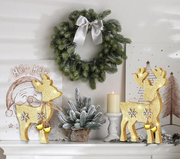 Wooden Christmas deer decorations near wreath and candle, showcasing affordable Christmas decor ideas for 2024.