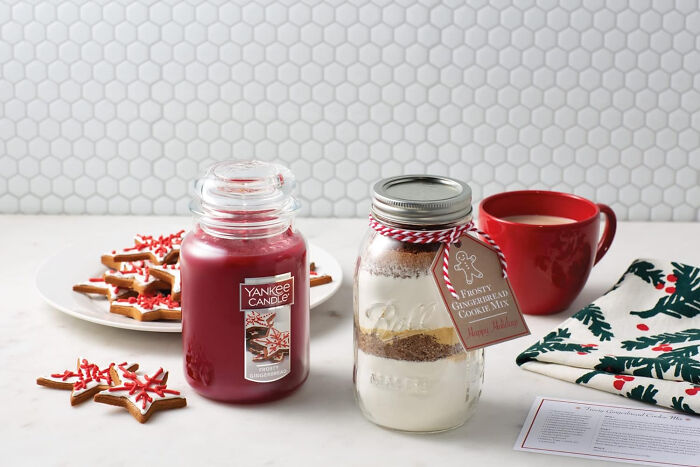 Red candle near festive biscuits and a cup of coffee showcasing affordable Christmas decor ideas for 2024.