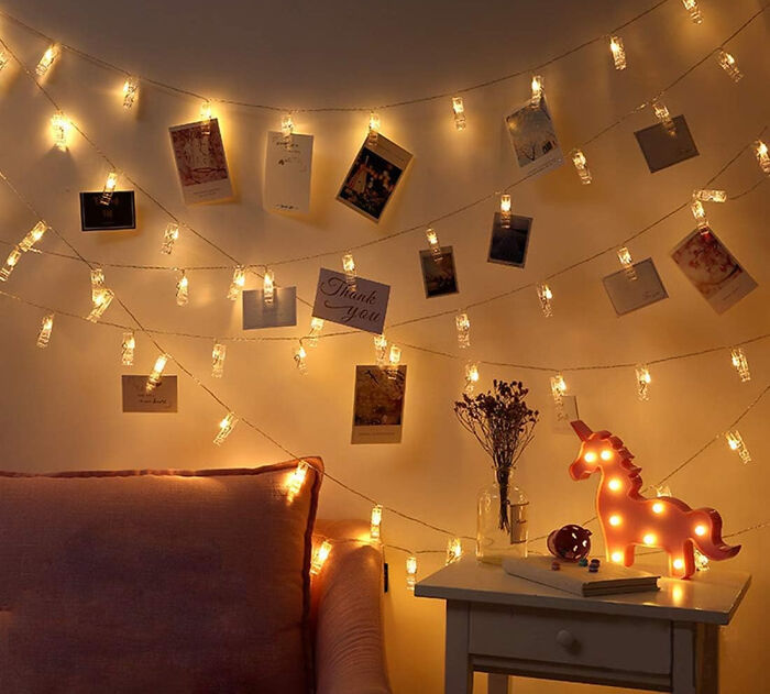 Polaroid pictures hanging in warm string lights creating affordable Christmas decor ideas with cozy ambiance.