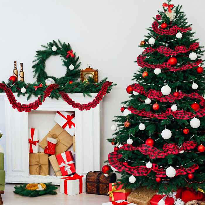 Green Christmas tree near fireplace decorated with red and white ornaments showcasing affordable Christmas decor ideas.