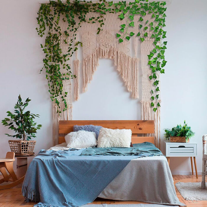 Cozy bedroom with a big bed and pillows, featuring affordable Christmas decor ideas using green plants and woven wall hangings.