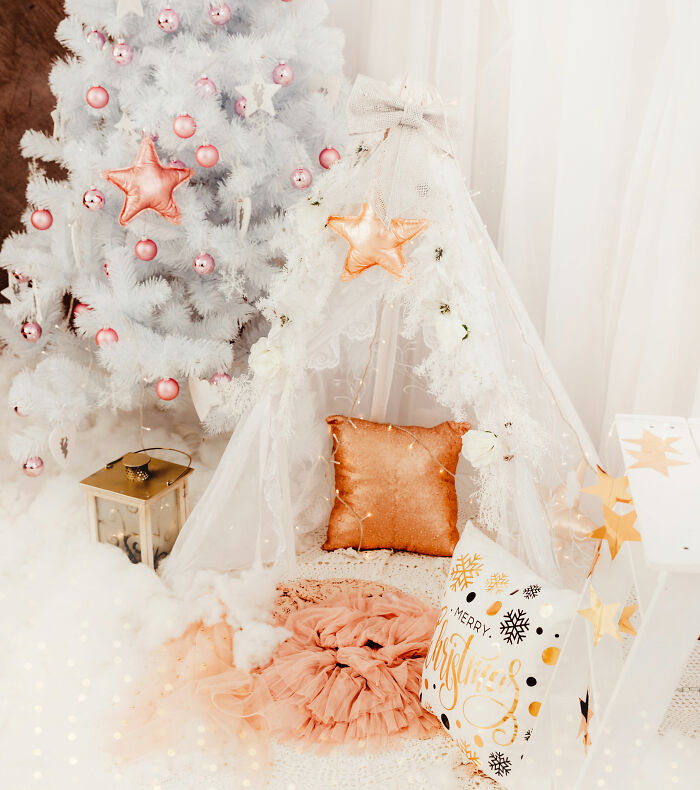 White Christmas tree and cozy white tent with gold pillow and festive affordable Christmas decor ideas for 2024.