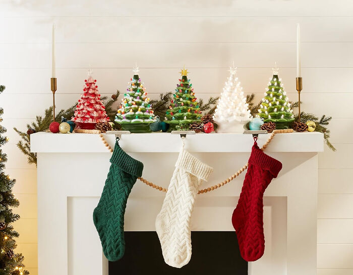 Small Christmas tree with glass baubles and affordable Christmas decor on a mantel decorated with stockings and greenery.