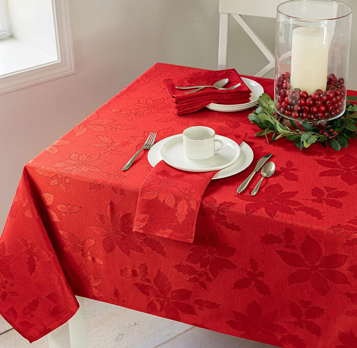 Red Christmas patterned tablecloth with matching napkins and festive candle centerpiece, showcasing affordable Christmas decor ideas.