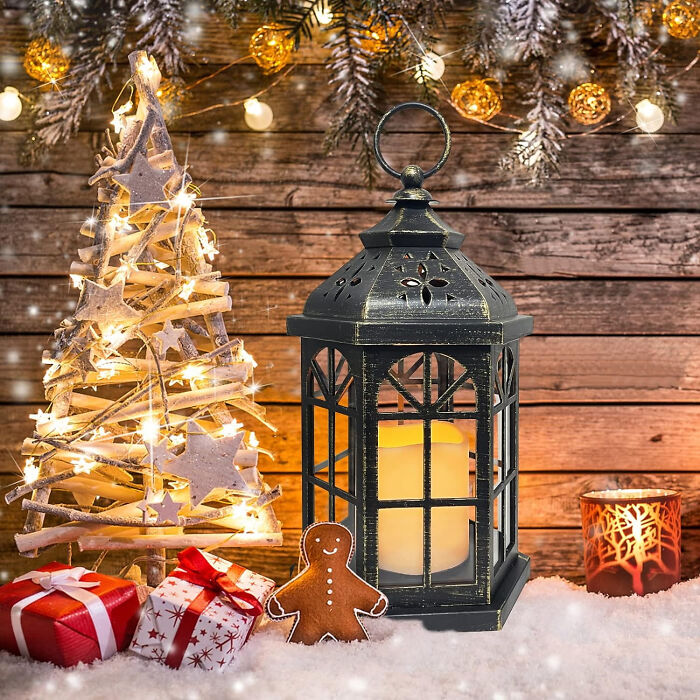Lantern with candle near Christmas tree lights, gifts, and gingerbread, showcasing affordable Christmas decor ideas.