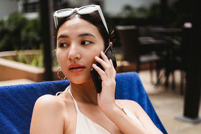 Young woman on phone outdoors looking away, representing normal workplace practices people want to disappear in future