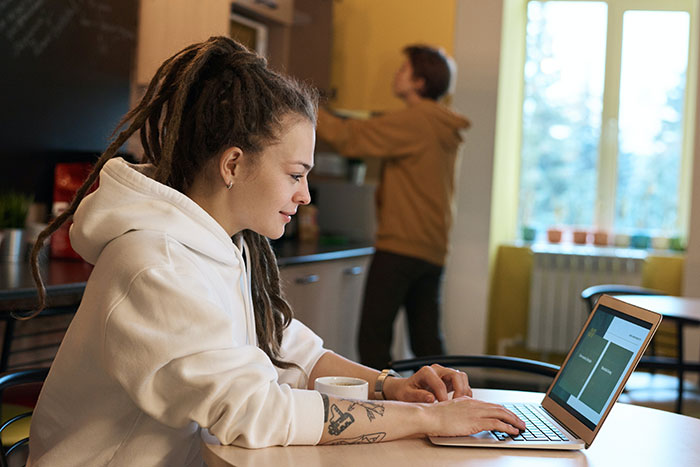 Young woman working on laptop in casual office, highlighting common workplace practices people wish would disappear.