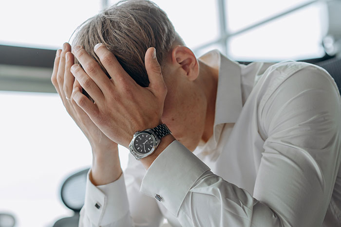 Man in white shirt showing frustration at workplace, illustrating common normal workplace practices issues.