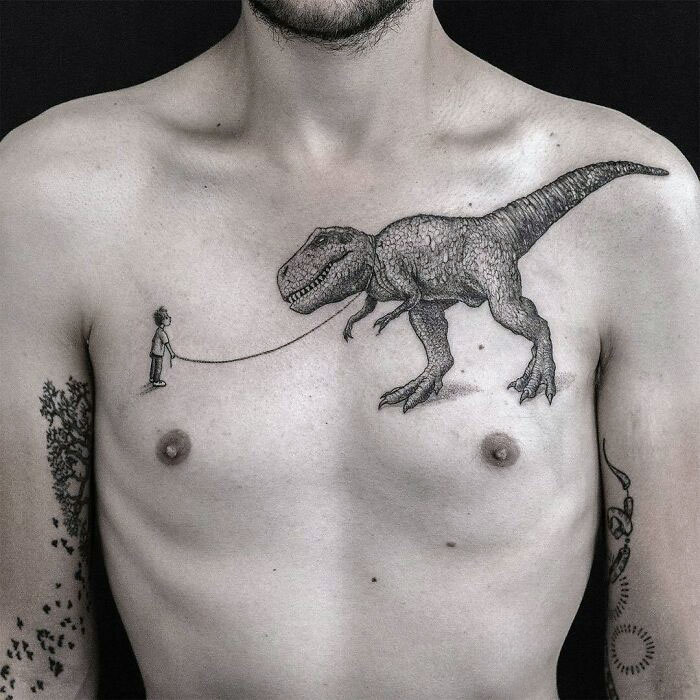 Man with detailed dinosaur tattoo of a T-Rex on his chest, depicting it on a leash.
