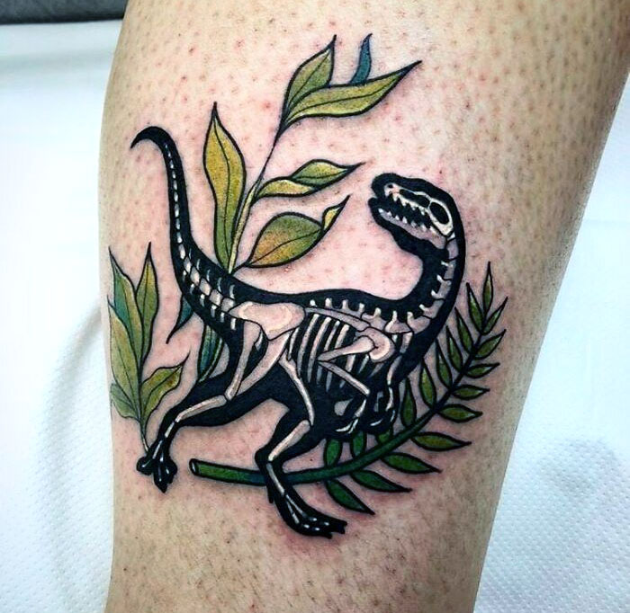 Dinosaur tattoo with plant motifs, showcasing a skeleton design on a person's skin.