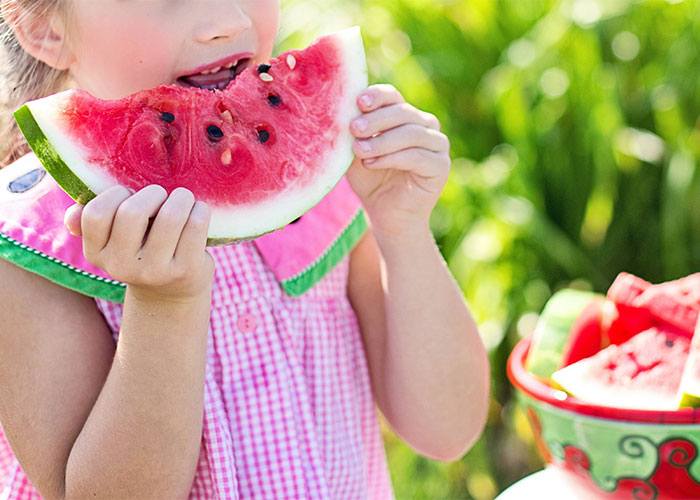 Young child eating watermelon outdoors symbolizing common outdated parenting myths about healthy eating and child habits.