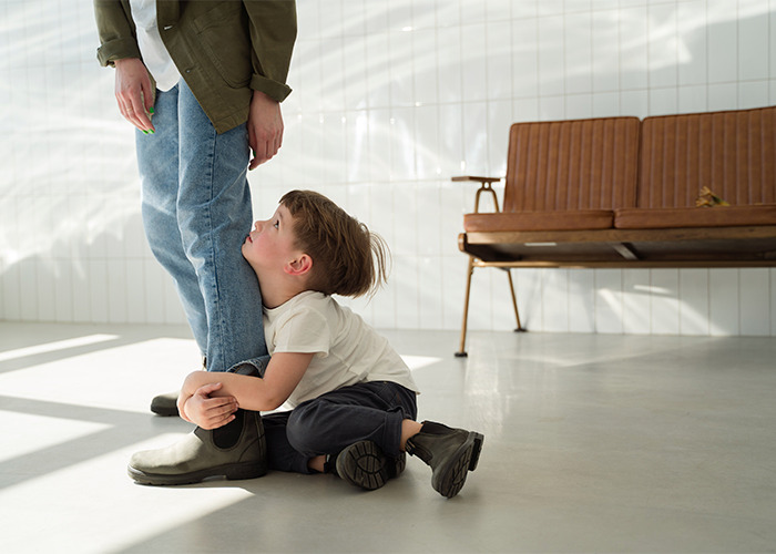 Young child hugging adult leg indoors, illustrating common outdated parenting myths about child behavior and attachment.