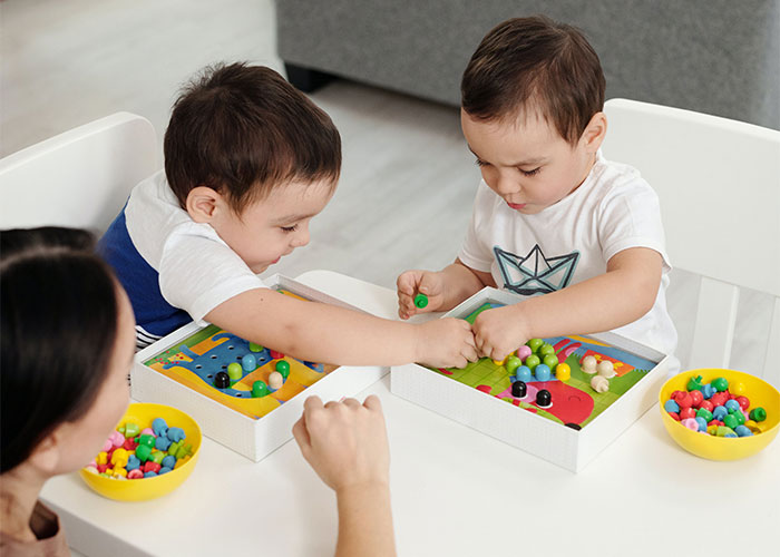 Two young children playing educational board games with colorful beads, illustrating outdated parenting myths.