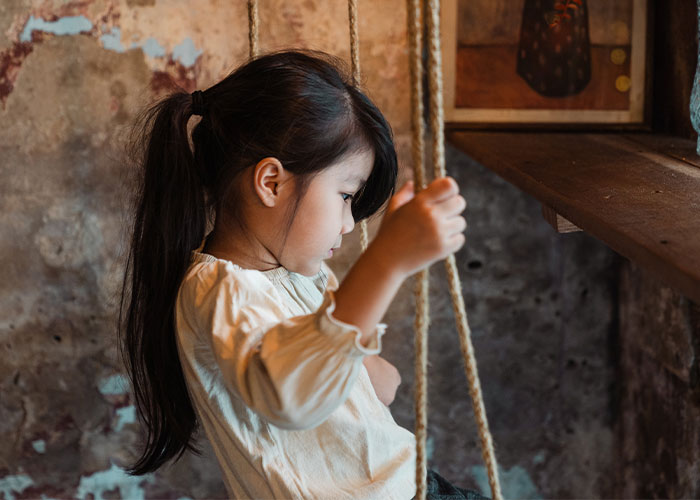 Young girl with long dark hair playing on a rope swing indoors, illustrating outdated parenting myths concept.