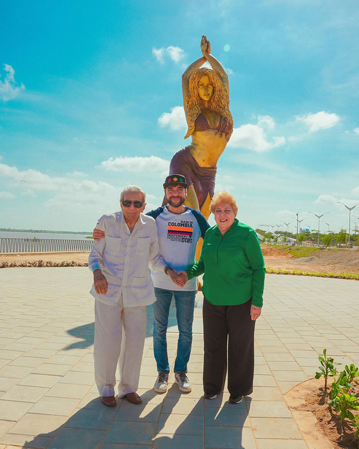 A group posing in front of a colossal Shakira statue in Colombia on a sunny day.