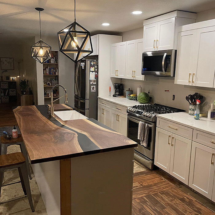 Modern kitchen featuring an epoxy countertop kitchen island with wooden accents and geometric pendant lighting.